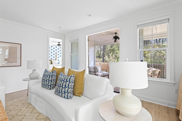 living room featuring baseboards, a healthy amount of sunlight, wood finished floors, and ornamental molding