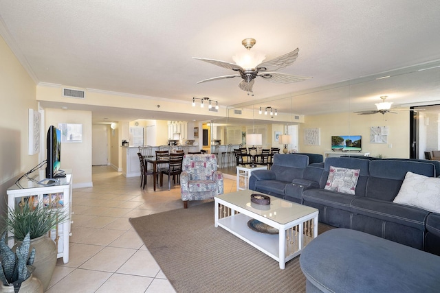 living area with visible vents, ornamental molding, a ceiling fan, a textured ceiling, and light tile patterned floors