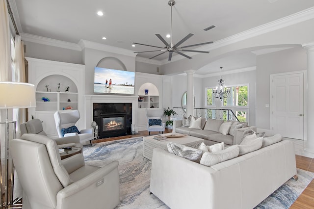 2940 Pine Valley Dr, Miramar Beach, FL 32550 - living area featuring ornamental molding, a fireplace, light wood-style flooring, decorative columns, and ceiling fan with notable chandelier
