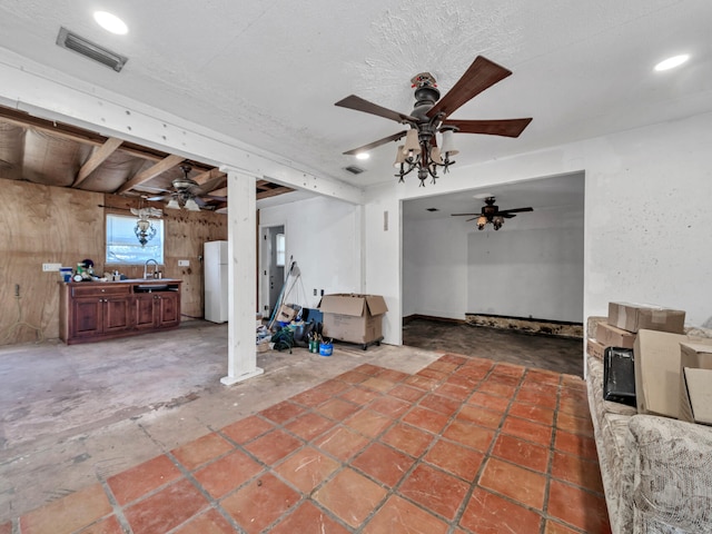 interior space featuring visible vents, freestanding refrigerator, a ceiling fan, and a sink