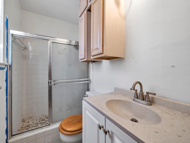 bathroom featuring a shower stall, toilet, and vanity