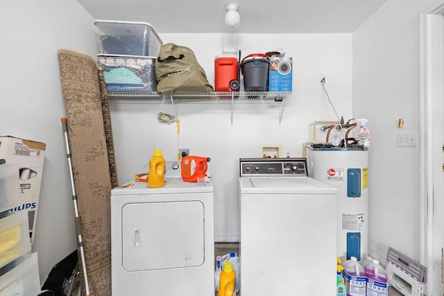 clothes washing area with laundry area, a textured ceiling, electric water heater, and separate washer and dryer