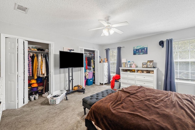 bedroom featuring visible vents, a ceiling fan, carpet flooring, and a textured ceiling