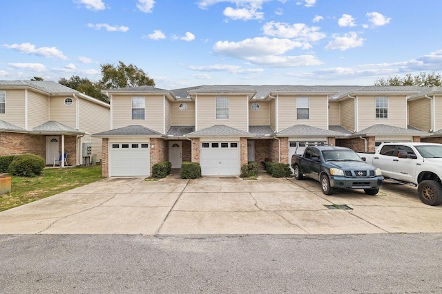 multi unit property featuring a garage, brick siding, and driveway