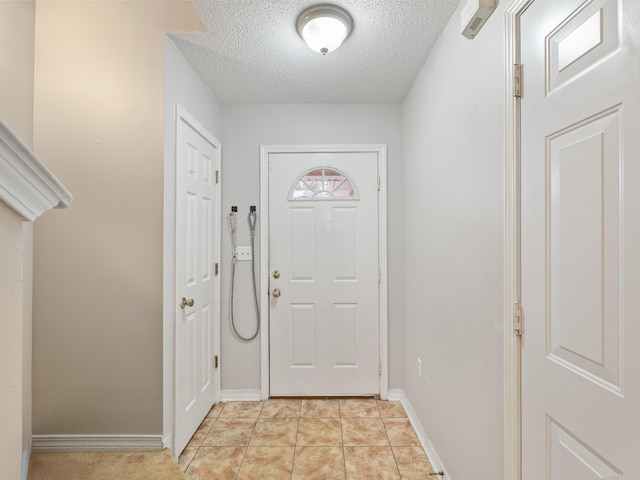 doorway featuring baseboards, a textured ceiling, and light tile patterned flooring