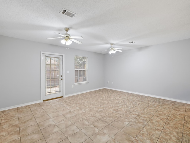 empty room featuring a ceiling fan, baseboards, visible vents, and a textured ceiling