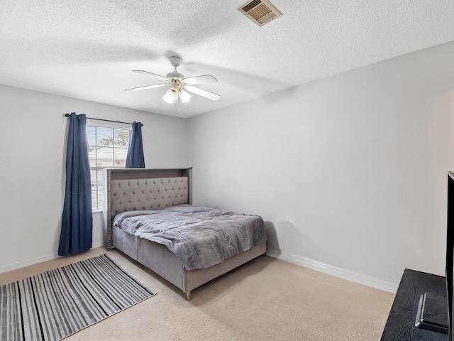 bedroom with visible vents, a textured ceiling, carpet floors, baseboards, and ceiling fan