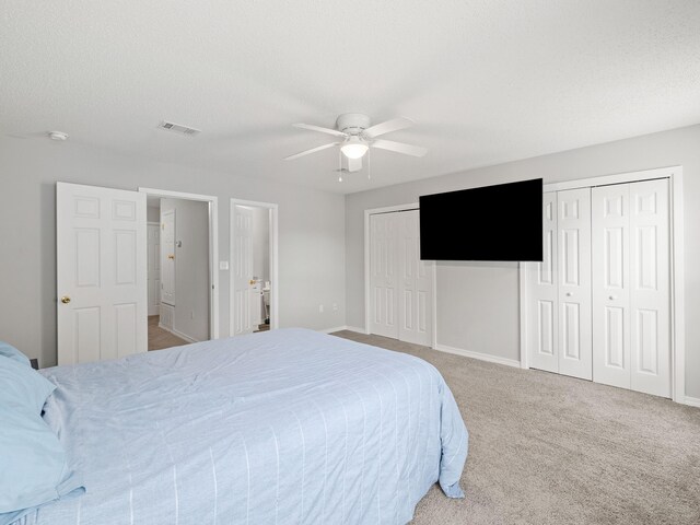 bedroom with visible vents, two closets, carpet flooring, a textured ceiling, and a ceiling fan