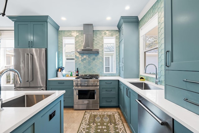 kitchen featuring light countertops, wall chimney exhaust hood, premium appliances, and a sink