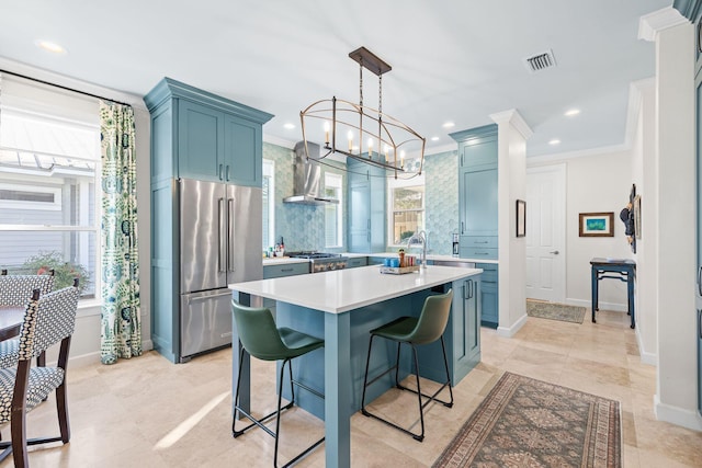 kitchen featuring light countertops, ornamental molding, high quality fridge, blue cabinets, and a kitchen island with sink