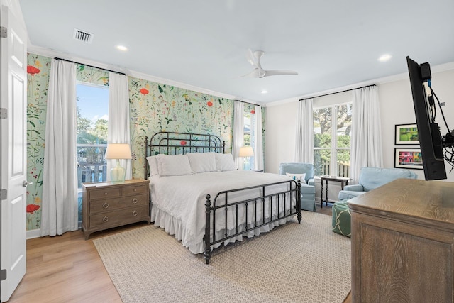 bedroom with visible vents, a ceiling fan, light wood-style floors, crown molding, and wallpapered walls