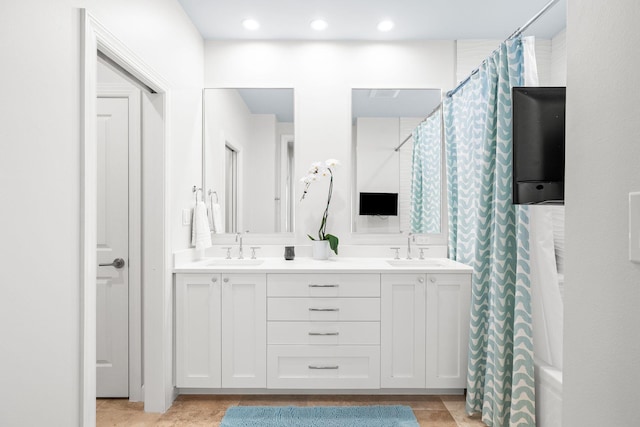 bathroom featuring double vanity, curtained shower, and a sink