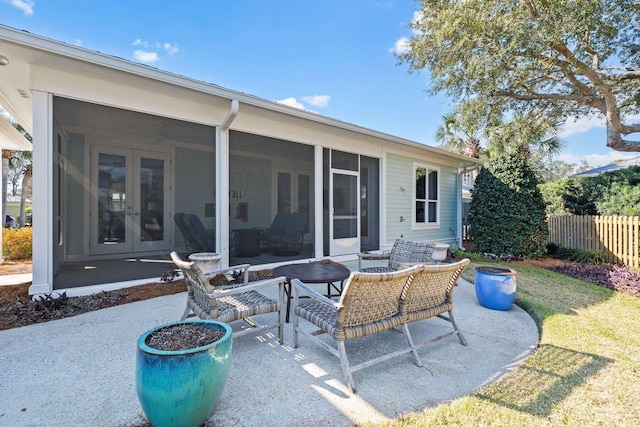 view of patio with french doors, fence, and a sunroom