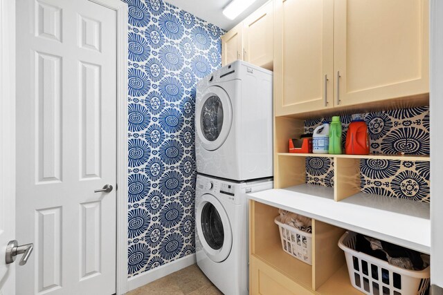 clothes washing area with cabinet space and stacked washing maching and dryer