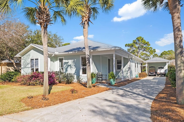 view of front facade featuring covered porch, concrete driveway, a front lawn, and metal roof