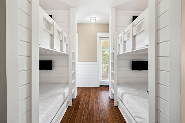 unfurnished bedroom with a wainscoted wall and dark wood-style floors