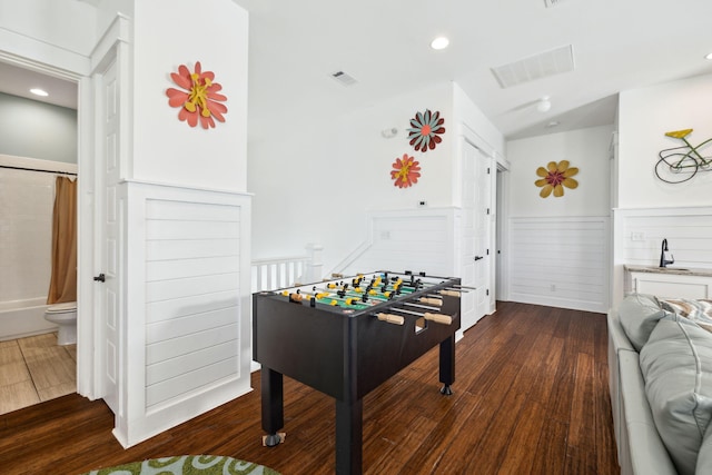 game room with dark wood finished floors, visible vents, a wainscoted wall, and a sink