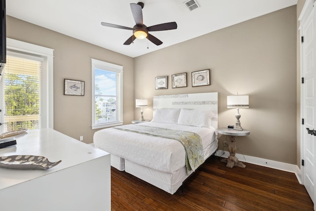 bedroom with dark wood-style floors, visible vents, multiple windows, and baseboards