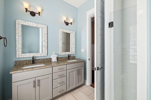 bathroom featuring double vanity, tiled shower, and a sink