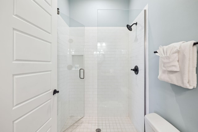 bathroom featuring toilet and a stall shower