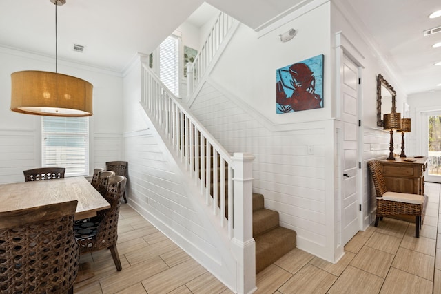 stairs featuring visible vents, crown molding, wood finish floors, and a wainscoted wall