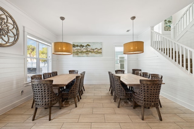 dining room with plenty of natural light, ornamental molding, and stairs