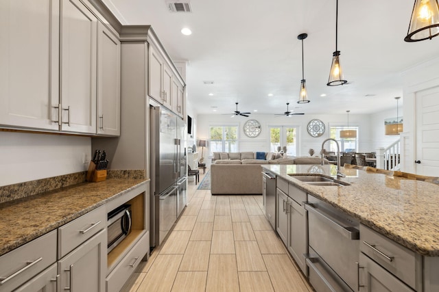 kitchen with visible vents, gray cabinetry, open floor plan, appliances with stainless steel finishes, and a sink