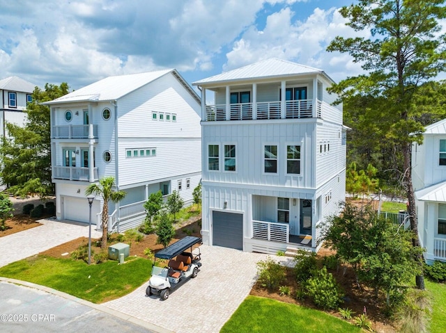 view of front of house featuring decorative driveway, board and batten siding, an attached garage, and metal roof