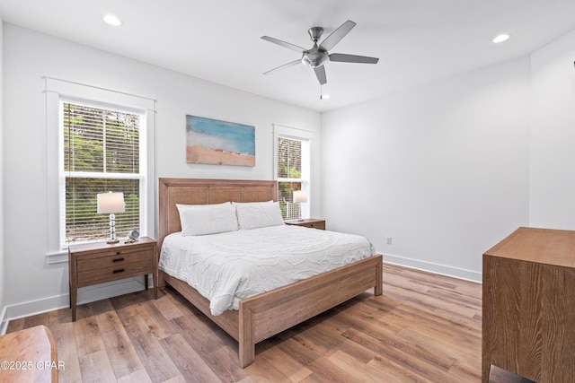 bedroom with multiple windows, light wood-type flooring, and baseboards