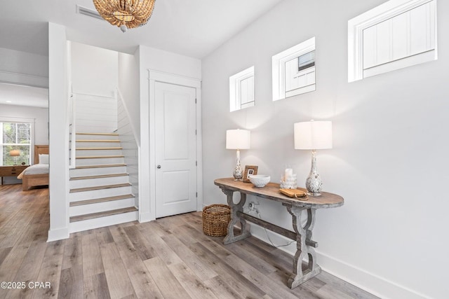foyer entrance with stairway, baseboards, visible vents, and wood finished floors