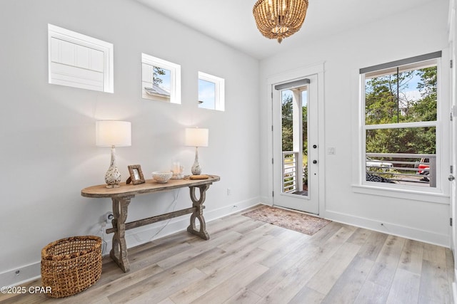 entrance foyer featuring baseboards, light wood-type flooring, and a chandelier