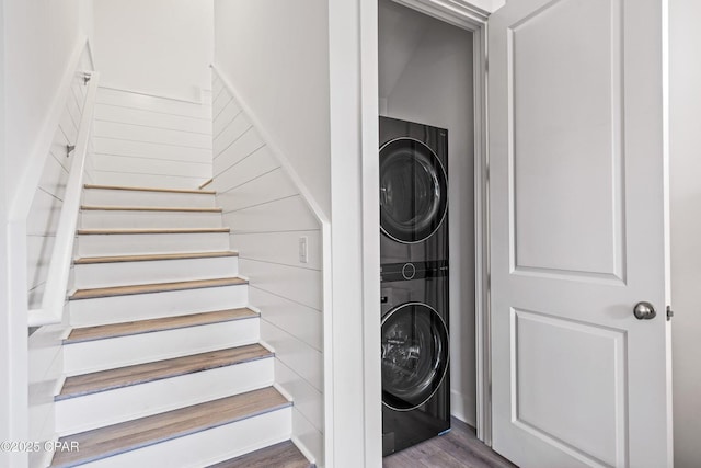 laundry room featuring laundry area, stacked washer and dryer, and wood finished floors