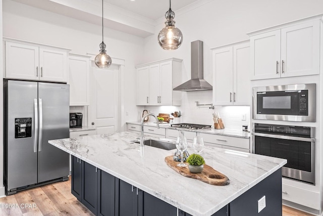 kitchen with a sink, white cabinetry, appliances with stainless steel finishes, wall chimney exhaust hood, and decorative backsplash