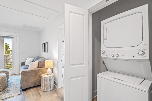 clothes washing area with laundry area, light wood-style floors, stacked washer and clothes dryer, and visible vents