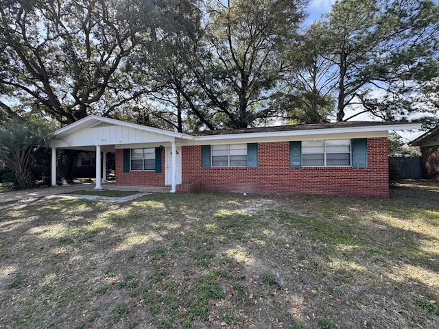 ranch-style house with brick siding, an attached carport, driveway, and a front lawn