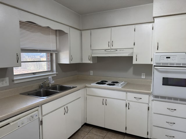 kitchen with under cabinet range hood, light countertops, tile patterned floors, white appliances, and a sink