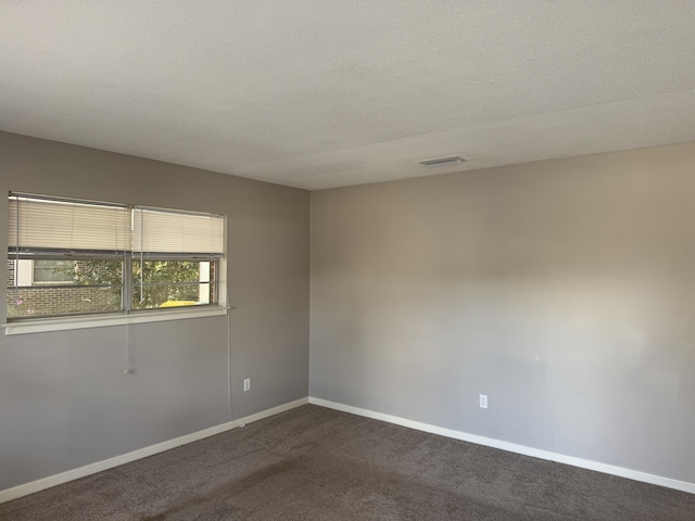 unfurnished room with visible vents, a textured ceiling, baseboards, and dark colored carpet