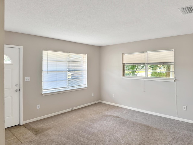 unfurnished room with visible vents, carpet flooring, a textured ceiling, and baseboards