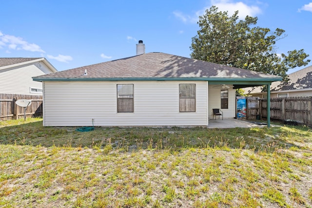 rear view of house with a patio area, a lawn, a chimney, and a fenced backyard