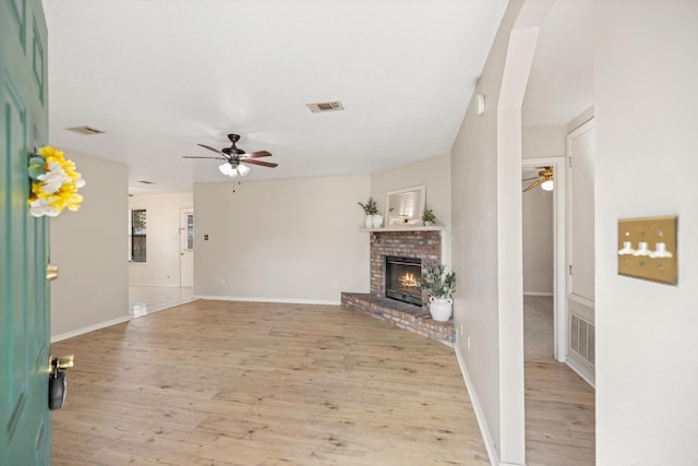 unfurnished living room with light wood finished floors, visible vents, and a ceiling fan