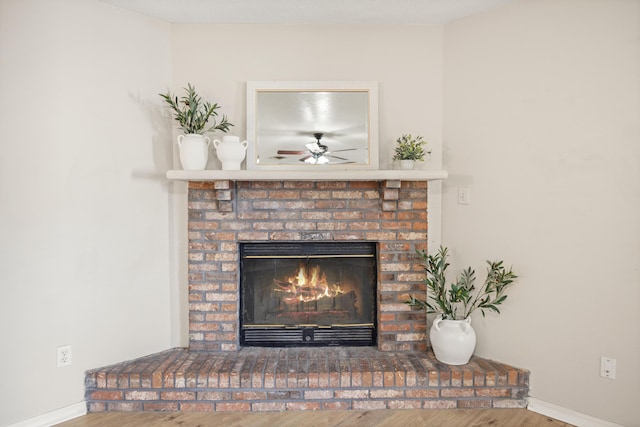 room details featuring baseboards, a ceiling fan, wood finished floors, and a fireplace