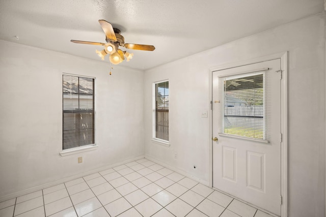 interior space with light tile patterned flooring, a textured ceiling, baseboards, and a ceiling fan