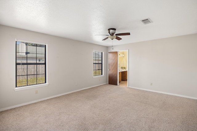 empty room featuring visible vents, plenty of natural light, light carpet, and a ceiling fan