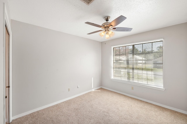 spare room with baseboards, light colored carpet, a ceiling fan, and a textured ceiling