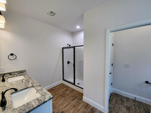 full bath featuring a stall shower, baseboards, wood finish floors, and a sink