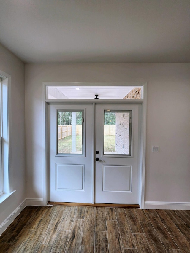 foyer featuring baseboards and dark wood-type flooring