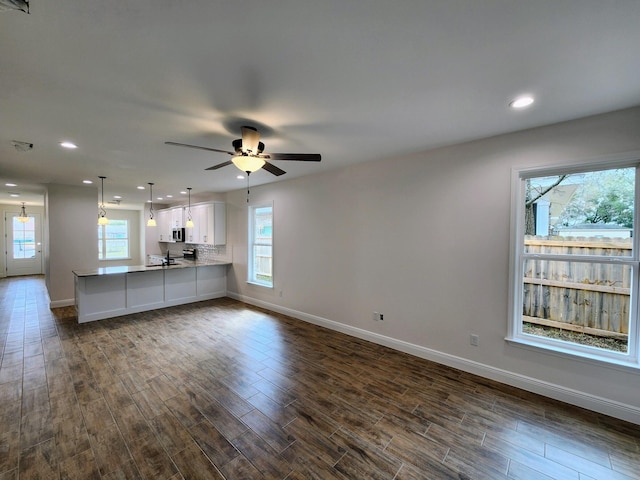 unfurnished living room with dark wood-type flooring, recessed lighting, a ceiling fan, and baseboards