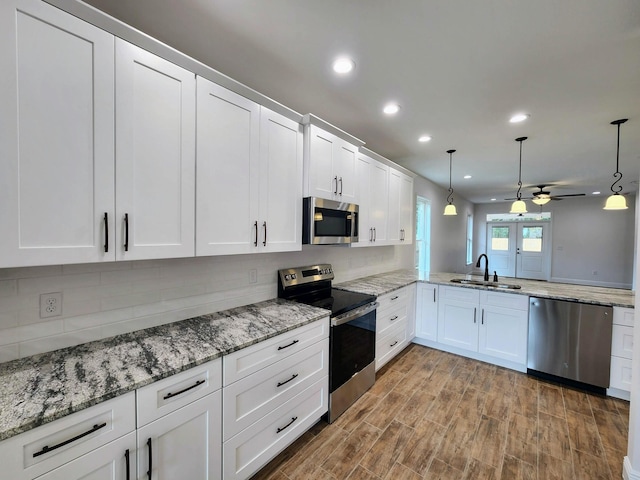 kitchen with a sink, tasteful backsplash, appliances with stainless steel finishes, white cabinets, and ceiling fan