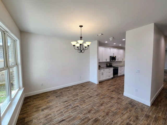 kitchen featuring dark wood finished floors, appliances with stainless steel finishes, baseboards, and an inviting chandelier