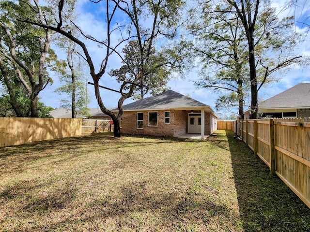 rear view of property with a fenced backyard, french doors, a lawn, a patio area, and brick siding